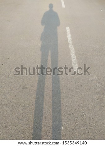 Someone's shadow on the pavement with a light reflection