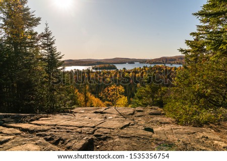 Entrelacs, Québec Canada - October 11 2019: Elevated Landscape View with Big Lake in Background and Autumn Colors amid Forest with Conifer Trees