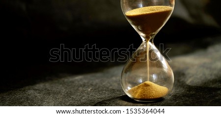 Dark mode of hourglass as time passing concept for business deadline, urgency and running out of time or life time concept