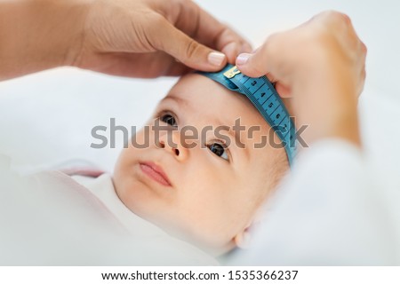 medicine, healthcare and pediatrics concept - female pediatrician doctor with measure tape measuring baby girl patient's head at clinic or hospital Royalty-Free Stock Photo #1535366237