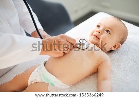 medicine, healthcare and pediatrics concept - close up of female doctor with stethoscope listening to baby girl's patient heartbeat or breath at clinic or hospital Royalty-Free Stock Photo #1535366249