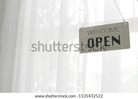Wooden signs with open words are welcome. White curtain background with copy spaces.