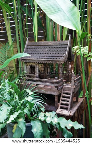 Wooden Thai spirit house shrine in natural green garden park- Thailand