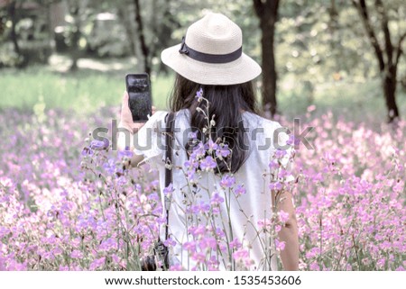 Young asian female tourist taking selfie by smartphone in garden of romantic trip to beautiful purple flower field.