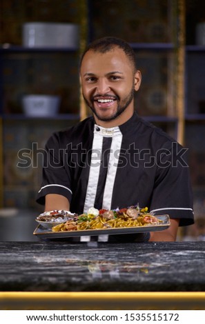 happy male chef presenting the dish in commercial kitchen