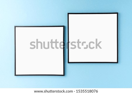 Two empty photo frames hanging on blue wall. Mockup