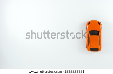 A red toy car on the white background in the top view which starts from the right hand in a verticle line