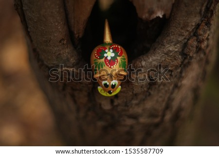 curious mouse looks down from the hollow tree