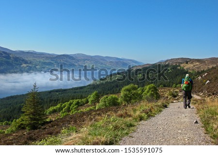Hiker on the "Great Glen Way" in Scotland, with Scottish highlands and loch in the distance Royalty-Free Stock Photo #1535591075