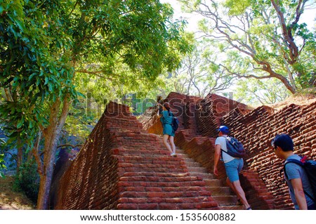 Tourists in Sigiriya climb the stairs and take pictures of monkeys