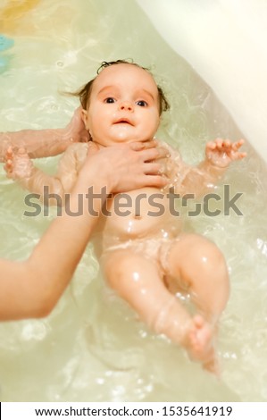 Small cute big-eyed beautiful baby bathes