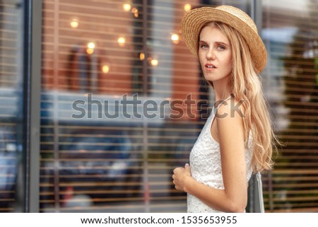 Young girl wearing hat standing on city street looking back thoughtful close-up