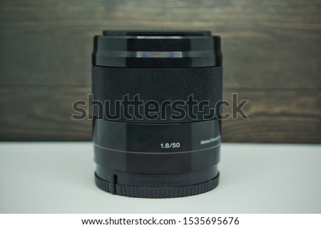 side view of a 50mm fixed lens with wooden background and white table