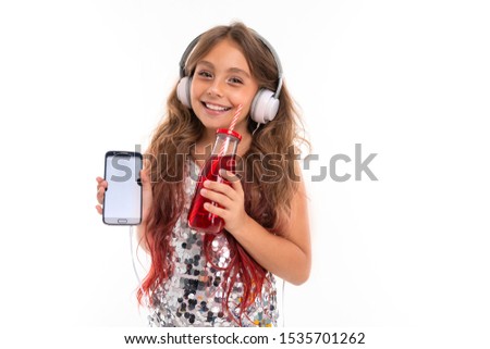 Smiling female kid with smartphone and alcohol-free drink in her hands