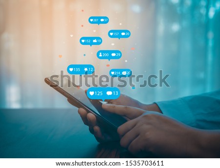 Person using a social media marketing concept on mobile phone with notification icons of like, message, comment and star above smartphone screen. Royalty-Free Stock Photo #1535703611