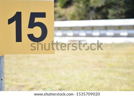Number 15 with black digits on a yellow plate outside on the shooting range