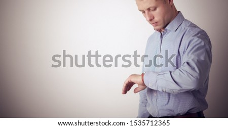 Businessman looking at watch, isolated on gray background