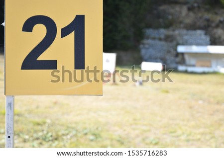 Number 21 with black digits on a yellow plate outside on the shooting range