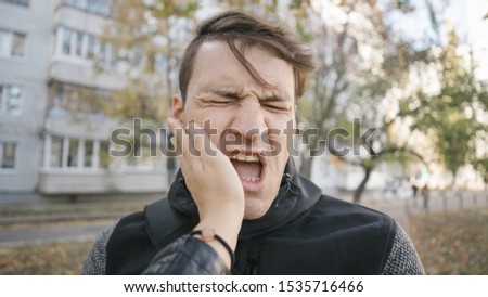 Man getting slapped in the street. Unhappy scared man getting slapped standing into the park Royalty-Free Stock Photo #1535716466