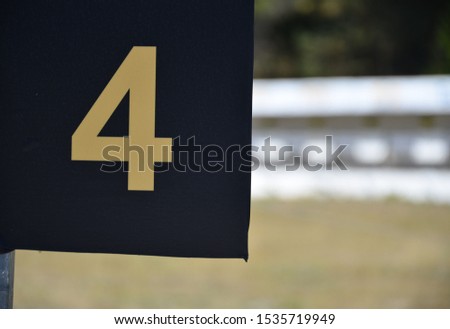 Yellow number 4 on a black plate outside on the shooting range
