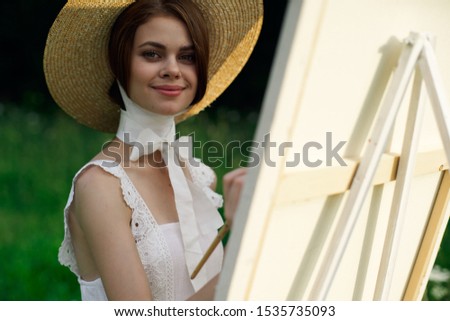 young woman in a beautiful hat looks at the camera outdoors