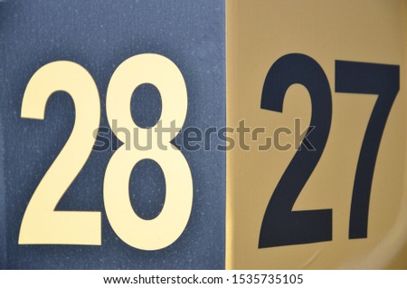 Number 27 and 28 next to each-other with black and yellow digits on a yellow and black plate