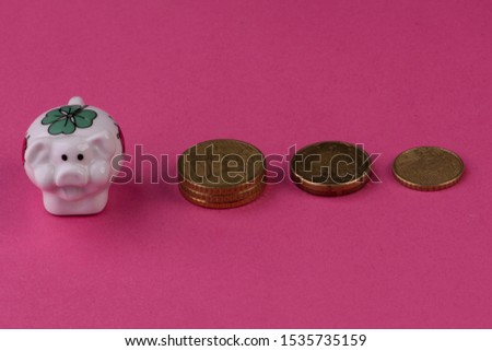 Lucky pig on pink background stacked with euro coins