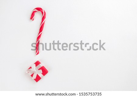 Question mark from Christmas present with candy cane on white background. Gift choice concept. Top view, flat lay, copy space