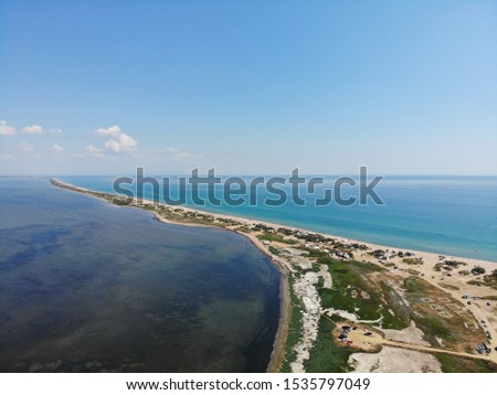 A narrow strip of land separating the sea and the lake. The blue expanse of the sea and the almost black expanse of the lake is a beautiful sight.