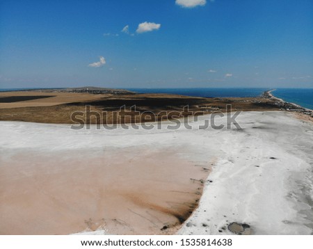 A dried-up lake next to the sea. The lake was so dry that the pink-and-white salt showed on the surface. The sea can not break through the strip of beach to save his younger brother water
