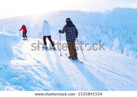Three athletes in ski helmet and ski. Against the background of a winter landscape and bright rays of the sun. Winter sports and family vacations