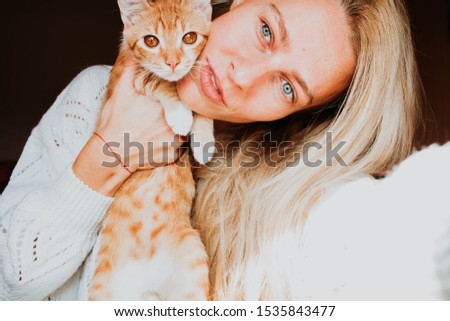 Portrait of blonde woman with blue eyes and ginger cute cat