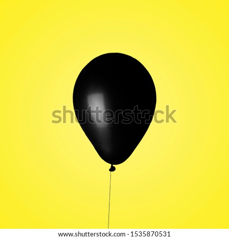 landscape design of a black balloon floating in front of a yellow background.isolated black ball bright background.suitable for Black Friday holiday, birthday and gifts, big discounts and shopping
