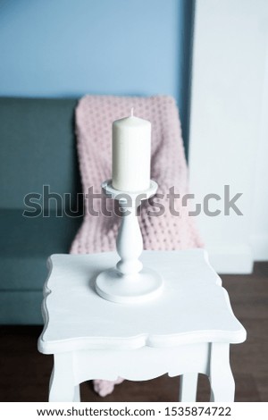 Stylish white big candle on a table, photo in soft pastel colors
