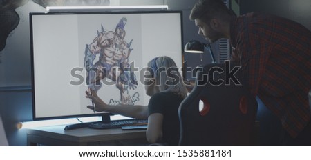 Medium shot of a male and a female video game developer discussing game art