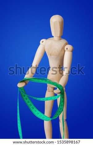 Wooden toy figure with measuring tape on blue background