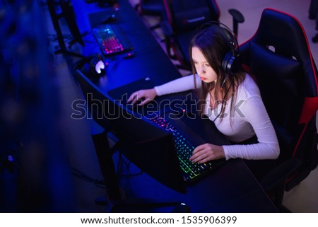 Streamer beautiful girl professional gamer smile playing online games computer with headphones, neon color.