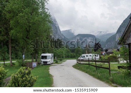 Camping area with campers and mountains and a cloudy sky in background, picture from Hallstatt Austria.
