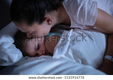 Close-up Of A Mother Lovingly Kissing Her Sleeping Daughter On Cozy Bed