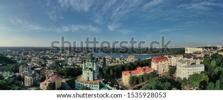Panoramic aerial view of the Podil neighborhood in Kyiv with its famous St. Andrew's Church and the Dnieper river on the background during sunny summer day