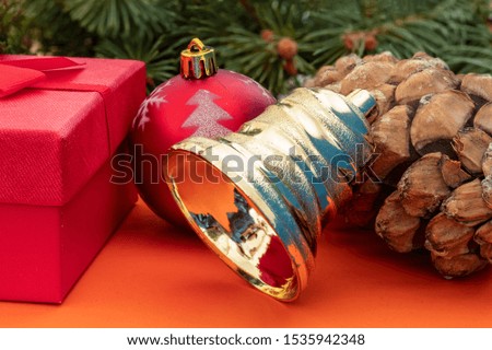 Creative Composition Useful for Christmas and New Year Greeting Card Created Using Red Gift Box, Decorative Christmas Ball, Christmas bell and Pine Cone