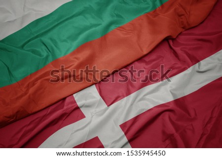 waving colorful flag of denmark and national flag of bulgaria. macro