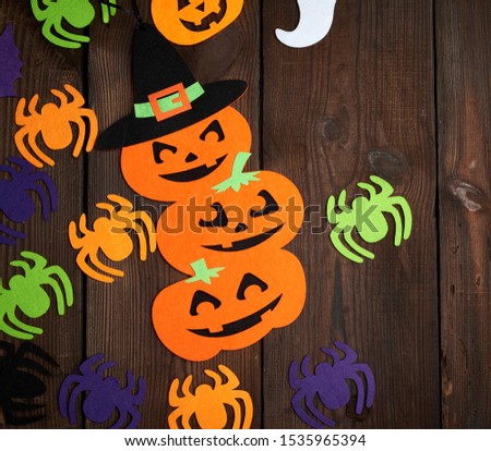 spider and orange pumpkin felt figures on a brown background, Halloween festive backdrop