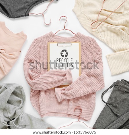 Recycle clothes concept. Pale pink knitted sweater with clipboard  on white background. Autumn and winter clothes. 