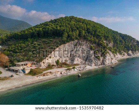 Iconic aerial view over Hovolo beach at Neo Klima village in Skopelos island. Mediterranean colors, green nature and rocky scenery over a famous Greek island in Autumn. Sporades, Aegean sea, Greece