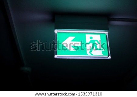Close-up picture of led sign in corridor point way out of resident apartment building, Fire warning exit with arrow symbol sign box. Emergency exit