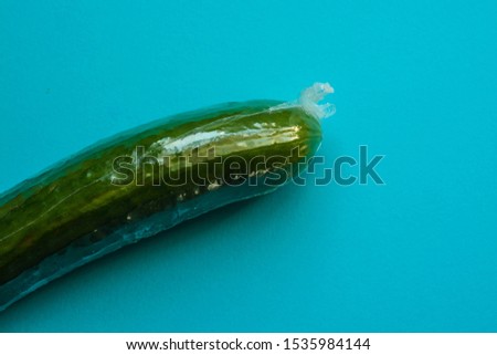 Cucumber wrapped in plastic against blue background  Royalty-Free Stock Photo #1535984144