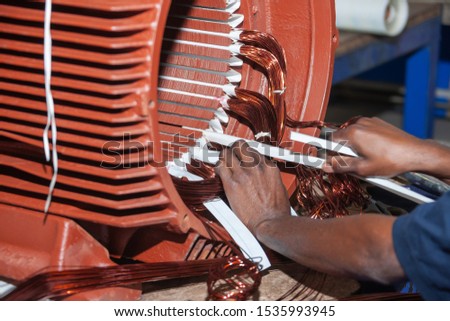 African man rewinding a giant electric motor Royalty-Free Stock Photo #1535993945