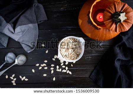 Halloween pumpkin and seeds on dark wooden background