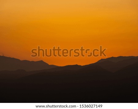 silhouettes of mountains at sunset with high orange contrast